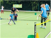 Coach teaching young child tennis.